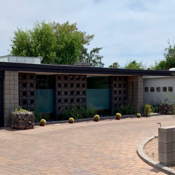 Mid-century modern home in Marion Estates Phoenix with circular breeze block, flat roofline, dark garage, desert landscaping, and block courtyard wall.
