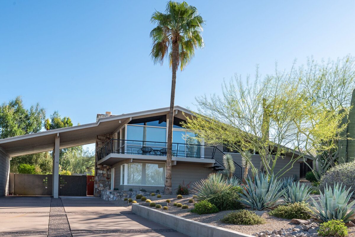 Unique two-story Ralph Haver mid-century modern home in Marion Estates Phoenix with balcony, low roofline, carport, palm trees, and desert landscaping.
