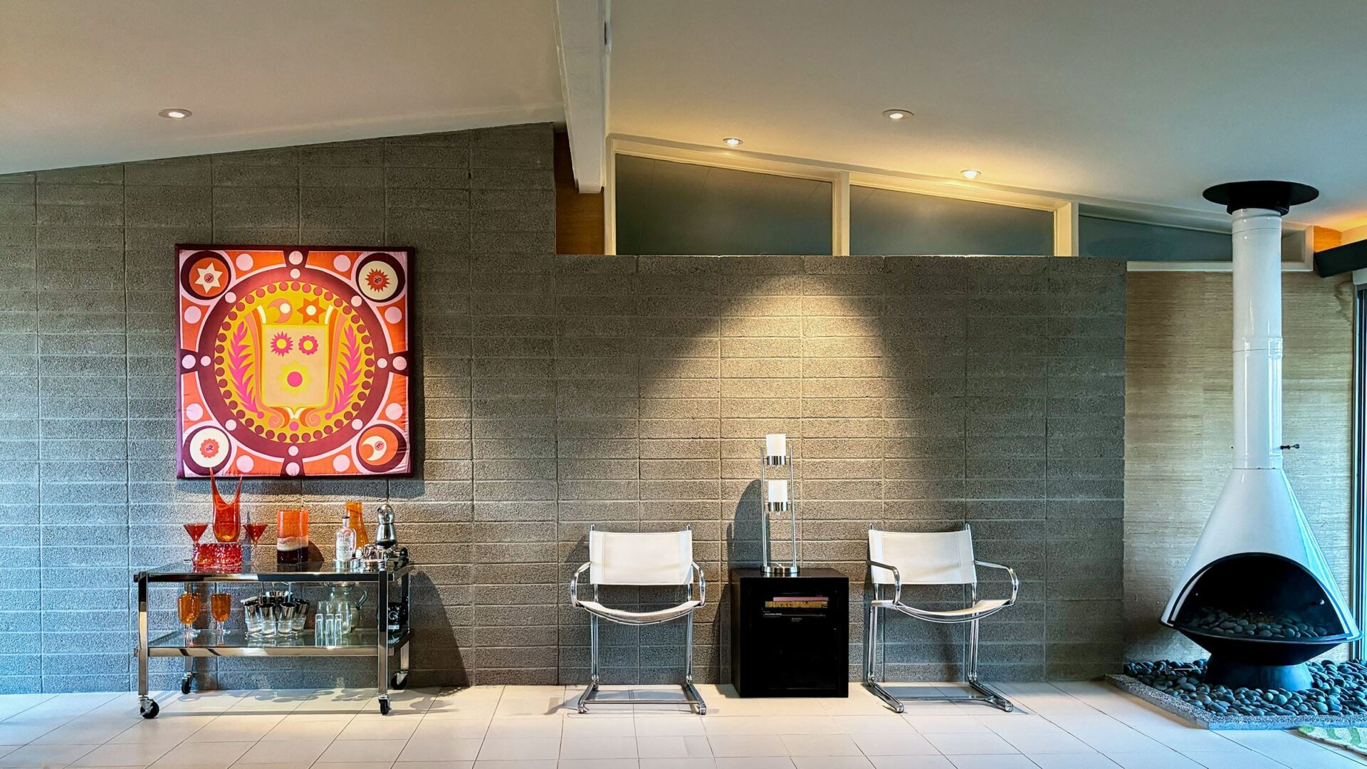 Mid-century modern interior with a freestanding Malm fireplace, warm wood details, and modern lounge seating.