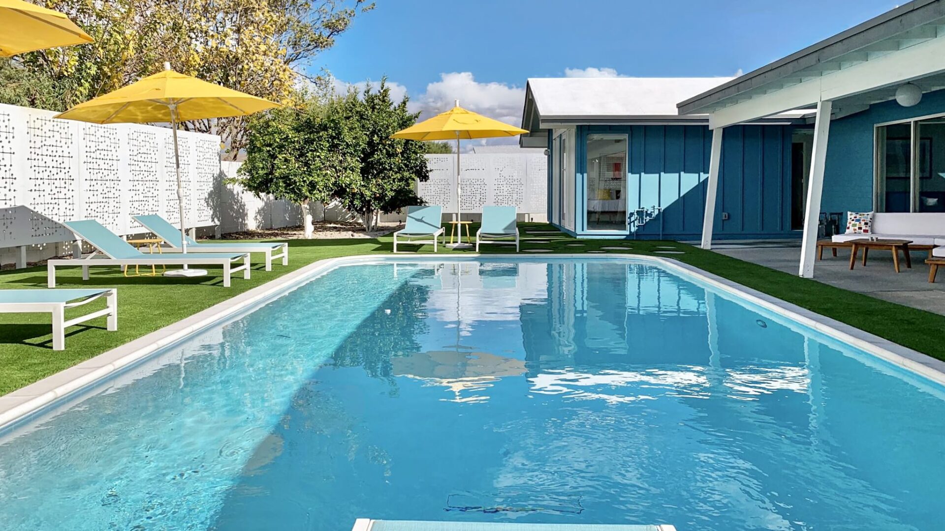 Modern pool and outdoor living space at Sheridan House in Scottsdale featuring custom privacy screens, artificial turf, lounge seating, and mid-century modern design.